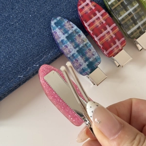 Gros plan détaillé des pinces à cheveux à carreaux pastel avec mécanisme métallique