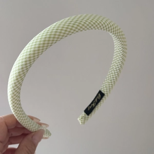 Detailed view of light green gingham headband featuring a black label with gold lettering