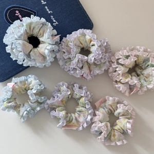 Détail de chouchous fleuris avec bords à volants en satin rose, violet et bleu pastel