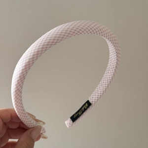 Close-up of pink and white plaid headband featuring an internal branded fabric label