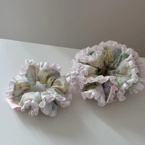 Vue détaillée de chouchous floraux faits main avec bords plissés blancs et détails satin