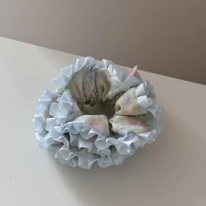 Détail d'un chouchou floral avec bords en satin bleu et motifs de fleurs roses