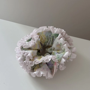 Gros plan d'un chouchou floral avec bords à volants blancs et motifs de fleurs pastel