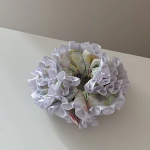 Gros plan du chouchou floral avec bords en dentelle plissée blanche et tissu mousseline