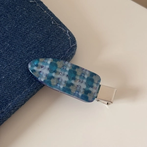 Vue macro d'une pince à cheveux en résine à motif floral bleu et clip en métal argenté
