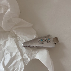 Dettaglio fermaglio per capelli a fiore argento con strass blu e base triangolare in metallo