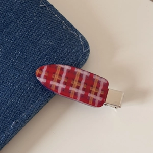 Détail d'une pince à cheveux à carreaux rouges sur une texture en denim bleu ciel