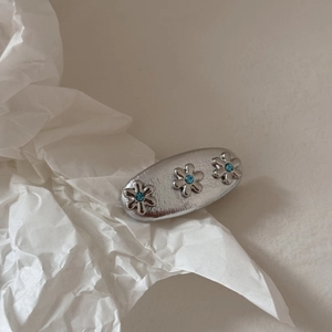 Dettaglio fermaglio per capelli in metallo martellato argento con tre fiori di strass blu
