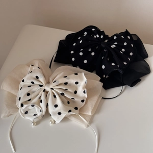 Détail de pinces à cheveux à nœuds à pois avec d'élégants pendentifs perles bicolores