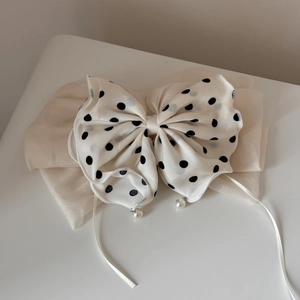 Détail d'une pince à cheveux à nœud pois avec mousseline plissée et pendentif perle