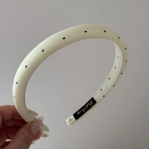 Detail showing the cream polka dot fabric headband texture and inner brand woven label