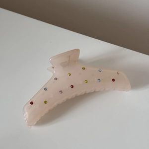 Vue détaillée de la pince à cheveux rose translucide ornée de strass colorés