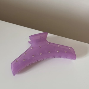 Détail d'une pince à cheveux violette translucide ornée de strass et de dents robustes