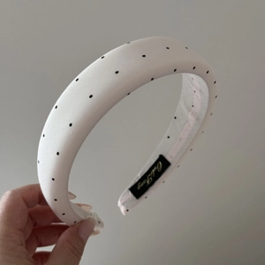 Detailed shot of retro padded polka dot headband featuring satin finish and brand label