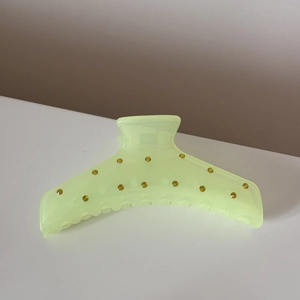Détail d'une pince à cheveux vert clair translucide avec des strass jaunes brillants