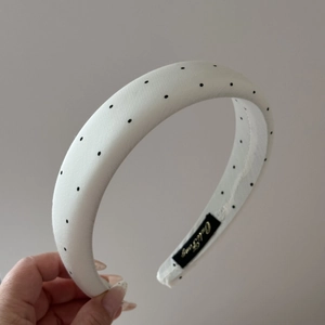 Close-up of padded white headband with black polka dots and satin lining detail