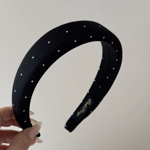 Detailed view of black polka dot satin headband with elegant brand label inside