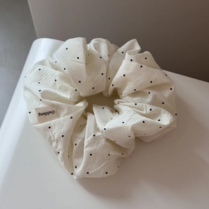 Detailed macro view of ivory white polka dot fabric scrunchie with elegant pleats