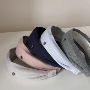Détail de serre-têtes larges en tissu coloré avec texture tricotée et breloques cœur argent