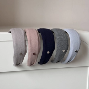 Détail de cinq serre-têtes en tricot aux tons pastels avec petits pendentifs en cœur