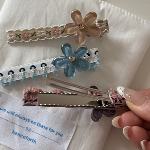 Détail de pinces à cheveux à ruban floral avec fleurs en résine et strass brillants