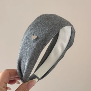 Gros plan sur un bandeau en tricot gris avec un petit pendentif en forme de cœur en argent
