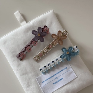 Vue détaillée de trois barrettes florales de luxe avec strass et texture de tissu