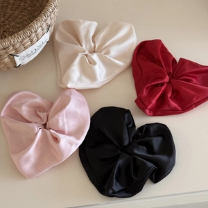 Close-up of four satin heart-shaped hair scrunchies in cream, red, pink, and black colors