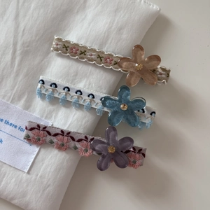Vue détaillée de trois barrettes à fleurs brodées dans les tons marron, bleu et violet