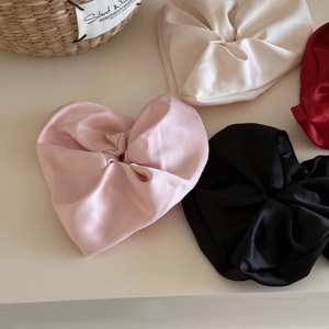 Satin heart-shaped hair scrunchies in pink, beige, black, and red with a silky finish