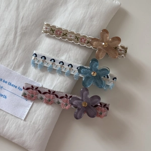 Détail d'un lot de trois barrettes florales avec strass et rubans en tissu doux