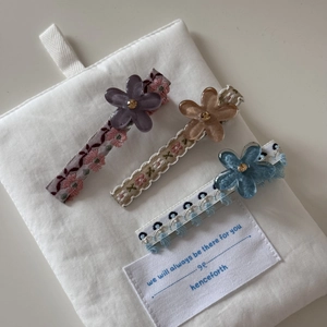 Détail de trois barrettes à fleurs avec pétales en résine, strass et rubans en dentelle