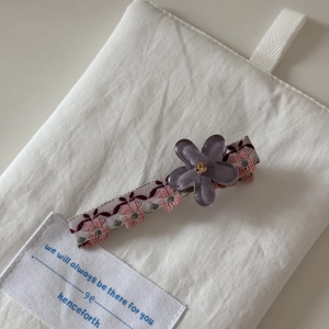 Détail d'une pince à cheveux avec broderie florale et fleur en strass violette