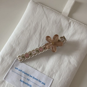 Détail d'une pince à cheveux avec fleur en résine, strass et ruban brodé élégant