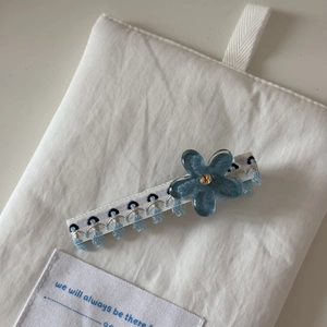 Détail d'une pince à cheveux fleur en résine bleue avec glands et tissu tissé blanc