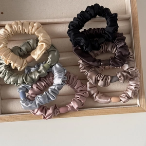 Detailansicht von Satin-Haargummis in Morandi-Farben mit glatten Schnallen