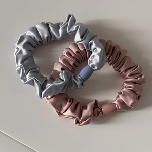 Detail von seidenähnlichen Satin-Haargummis in Metallic-Blau und Rosérosa Farben