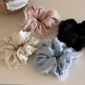 Detail view of four satin hair scrunchies with elegant lace edges in multiple colors