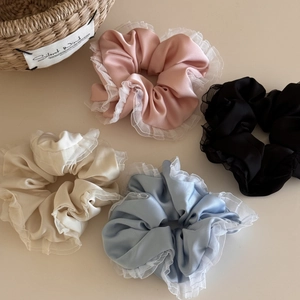 Set of four satin scrunchies with ruffled organza edges in pastel pink, black, and cream colors