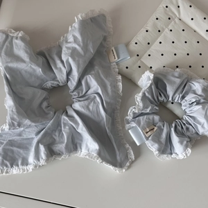 Close-up of light blue fabric scrunchies with white lace edges and handmade label