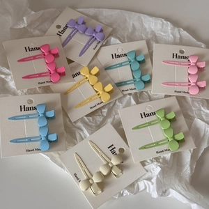 Paire de barrettes à cheveux en métal en forme de nœud aux couleurs macaron sur fond blanc
