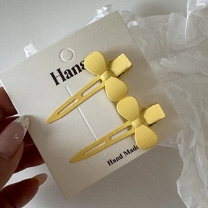 Détail de deux barrettes à cheveux nœud jaune mat en métal sur une carte de support