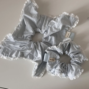Detail of light blue fabric hair scrunchies with white lace edges and Hand Made label