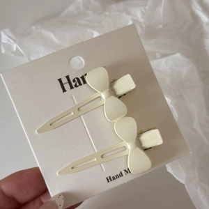 Lot de deux pinces à cheveux blanc crème avec relief nœud et finition mate sur carte support