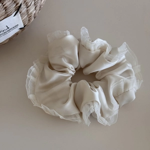 Detailed view of cream ruffled satin scrunchie with layered organza fabric and soft texture