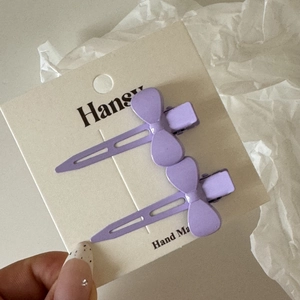 Détail de deux barrettes violettes mates avec nœuds pour la coiffure et le maquillage