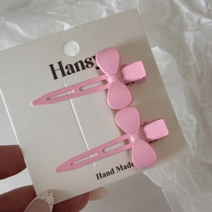 Gros plan d'une paire de barrettes à nœud rose sur carte d'affichage faite main