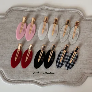 Detailed macro view of 12 oval acetate hair clips in six colors on a fabric tray