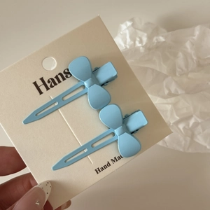 Détail de deux barrettes à cheveux nœud bleu clair mat sur une carte de présentation