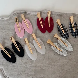 Flat oval acetate hair clips in assorted colors and textures on linen fabric